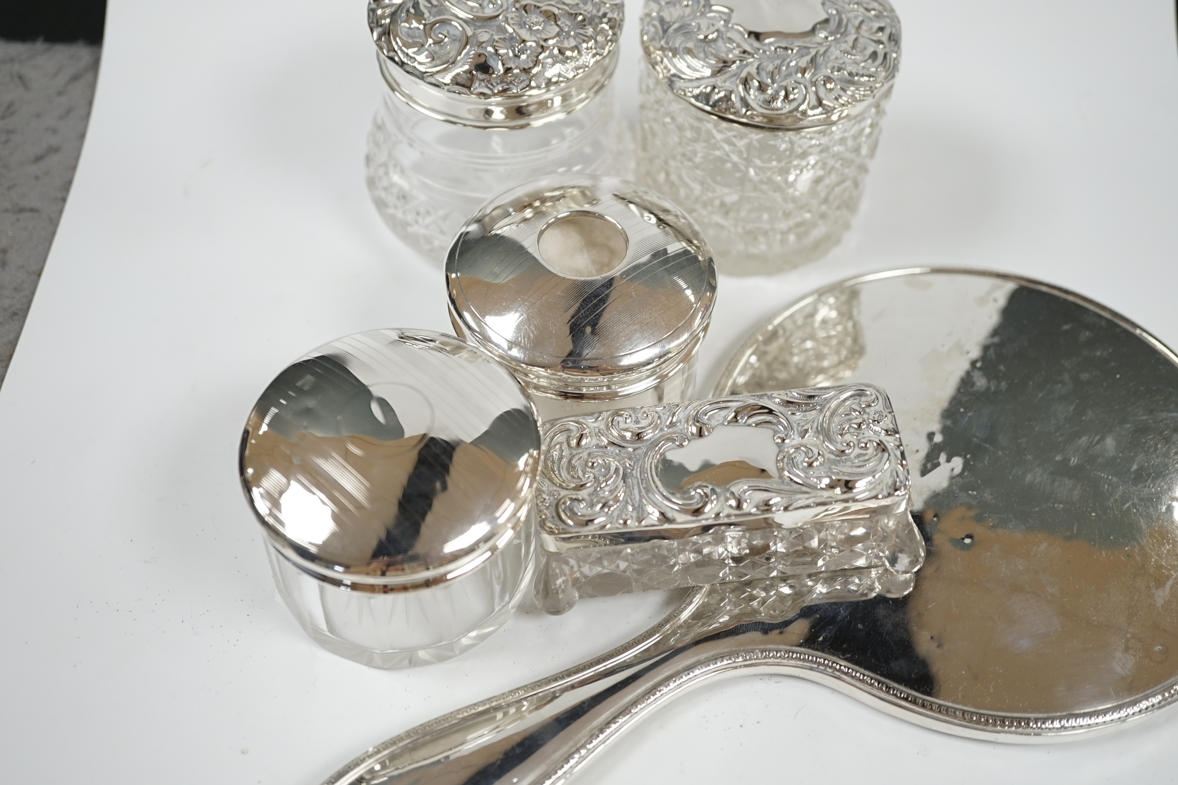 A silver hand mirror, marks rubbed and five assorted silver mounted glass toilet jars. Condition - poor to fair
